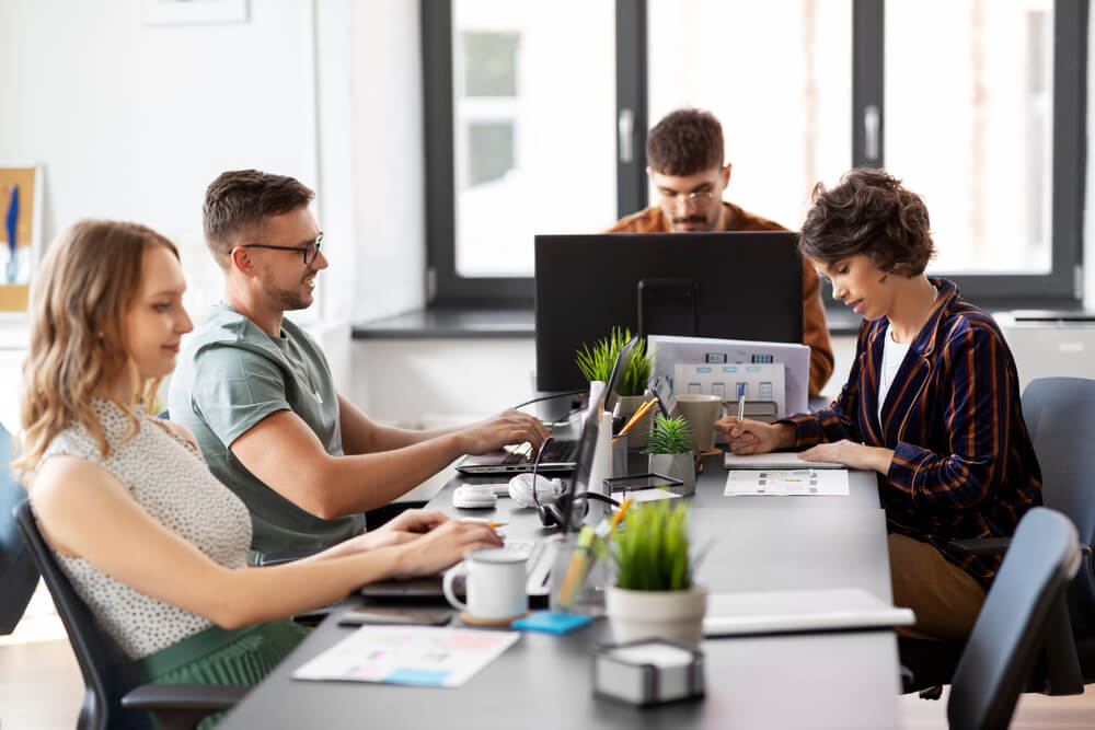 A diverse team of professionals collaborating at a desk in a modern office setting.