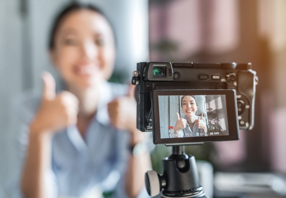 closeup image of a camera while taking marketing video of a dental worker in the background
