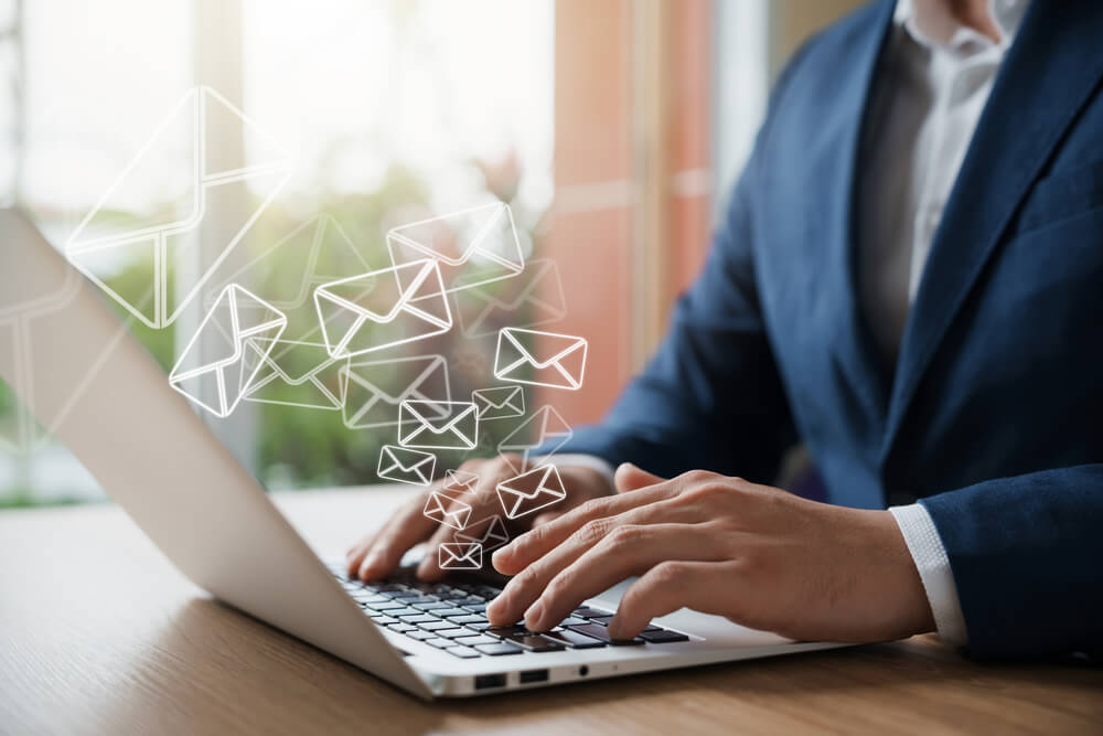 A business professional using a laptop with email icons, representing email marketing.
