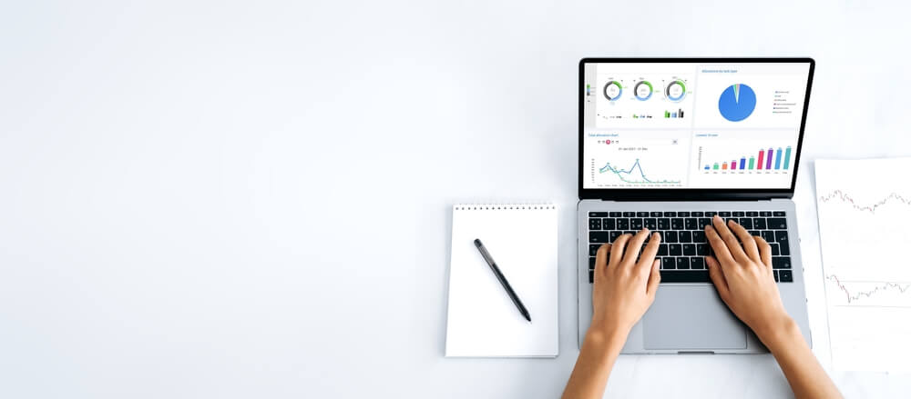 A person's hands on a laptop displaying graphs and charts.