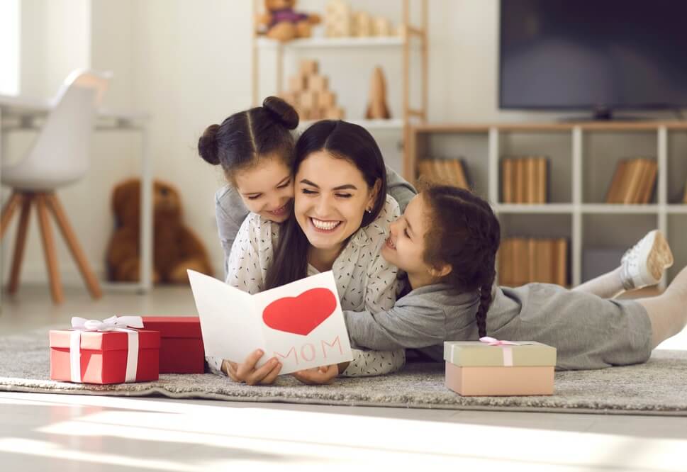 a mother doting with daughters and smiling while reading a greeting card